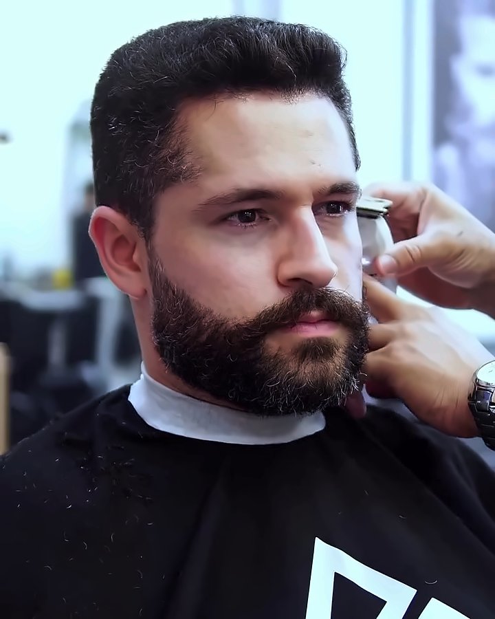 Cliente de barba cheia durante o acabamento com a máquina