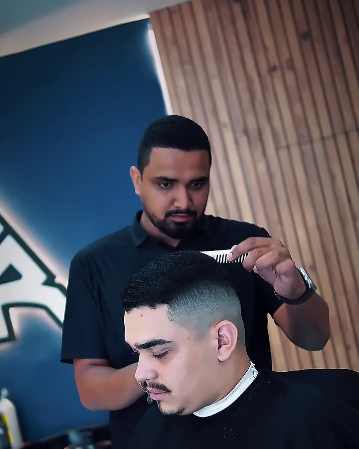 Barbeiro finalizando um degradê diante do triângulo da Borva