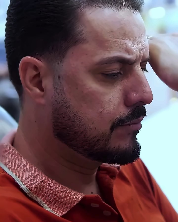 Cliente de perfil com o cabelo penteado e a barba alinhada