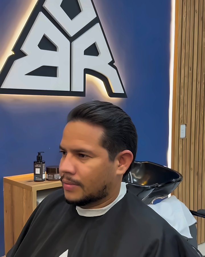Cliente na cadeira diante do triângulo da Borva aceso na parede azul